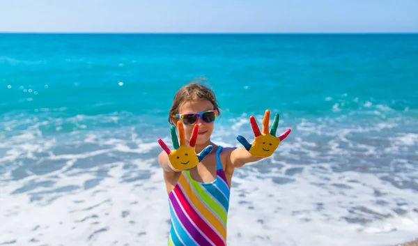 Child hands painted with paints on the sea. Selective focus. Kid.