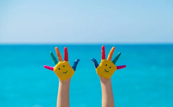 Child hands painted with paints on the sea. Selective focus. Kid.