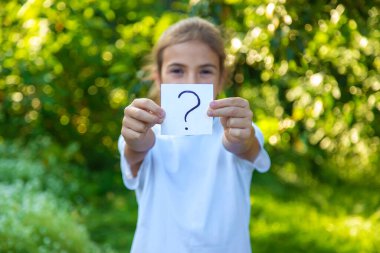 Çocuk üzerinde soru işareti olan bir kağıt tutuyor. Seçici odaklanma. Çocuk.