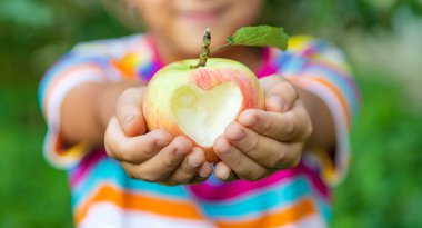 Çocuk bahçede bir elma yiyor. Seçici odaklanma. Çocuk.