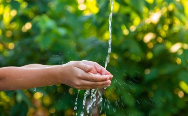 Su, çocuğun ellerine doğru akmaktadır. Seçici odaklanma. Doğa.