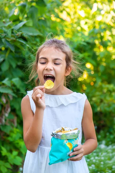 The child is eating chips. Selective focus. Kid.