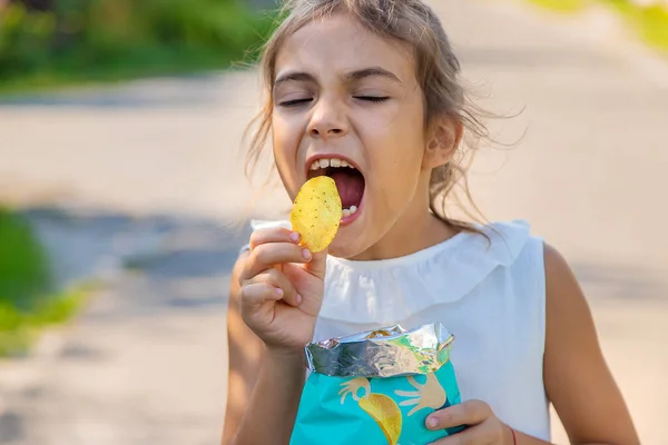 The child is eating chips. Selective focus. Kid.