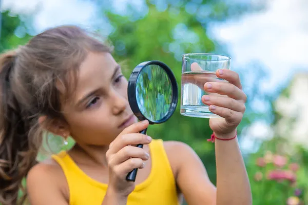 Criança Examina Copo Água Com Uma Lupa Foco Seletivo Miúdo — Fotografia de Stock