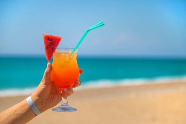 Bir kadın elinde denizin arka planına karşı bir kokteyl tutuyor. Seçici odaklanma. Doğa.