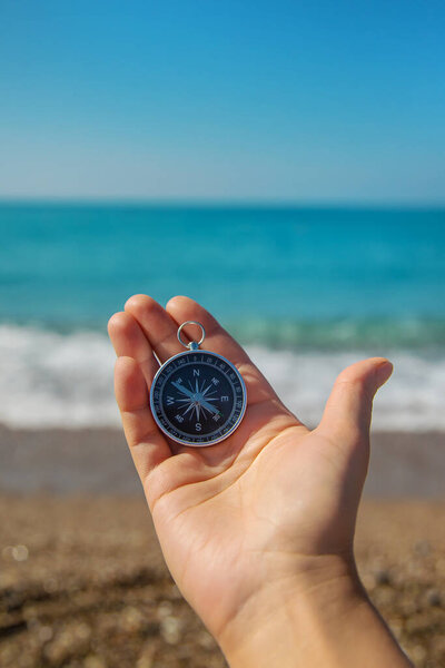 Compass in hands against the background of the sea. Selective focus. Travel.