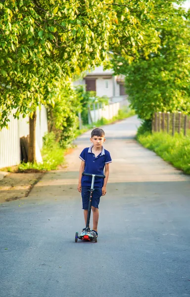 Çocuk sokağın aşağısında bir scooter kullanıyor. Seçici odaklanma. Çocuk.