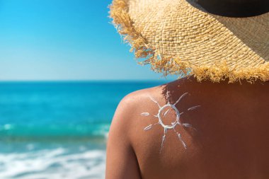 Sırtında güneş kremi olan bir kadın. Seçici odaklanma. Deniz.