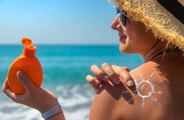 Sırtında güneş kremi olan bir kadın. Seçici odaklanma. Deniz.