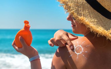 Sırtında güneş kremi olan bir kadın. Seçici odaklanma. Deniz.