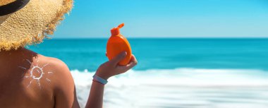 Sırtında güneş kremi olan bir kadın. Seçici odaklanma. Deniz.