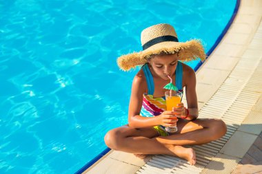 Çocuk havuz kenarında bir kokteyl içiyor. Seçici odaklanma. Çocuk.