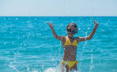 A child splashes water on the sea. Selective focus. People.