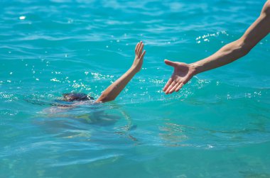 The child is drowning in the water the hand of salvation. Selective focus. People.