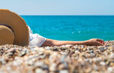 Woman with hat on the beach. Selective focus. Sea.