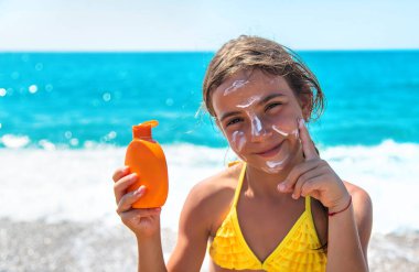 Çocuk yüzüne güneş kremi sürüyor. Seçici odaklanma. Çocuk.