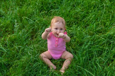 The child sits on the grass in summer. Selective focus. Nature.