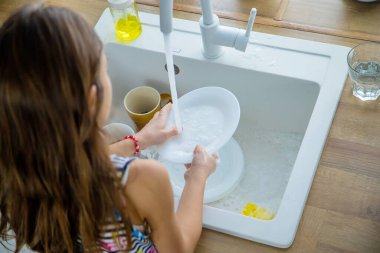 Çocuklar mutfakta bulaşıkları yıkarlar. Seçici odaklanma. Çocuk.