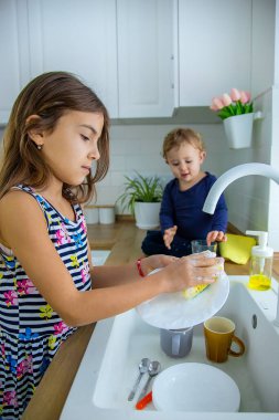 Çocuklar mutfakta bulaşıkları yıkarlar. Seçici odaklanma. Çocuk.