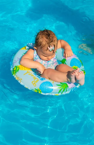 El bebé en la piscina nada en círculo. Enfoque selectivo. —  Fotos de Stock