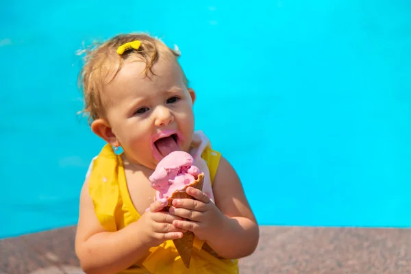 L'enfant mange de la glace près de la piscine. Concentration sélective. — Photo
