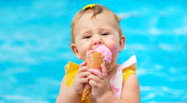 L'enfant mange de la glace près de la piscine. Concentration sélective. — Photo
