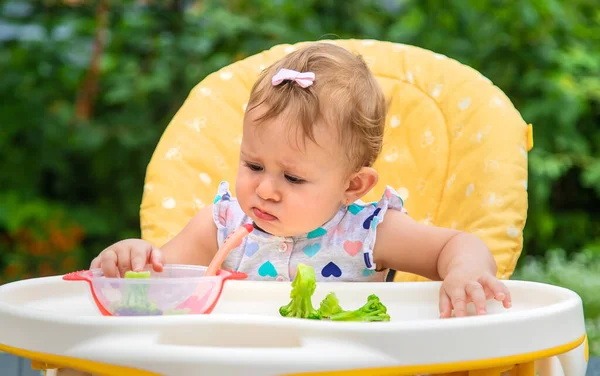 El bebé come trozos de verduras de brócoli. Enfoque selectivo. —  Fotos de Stock