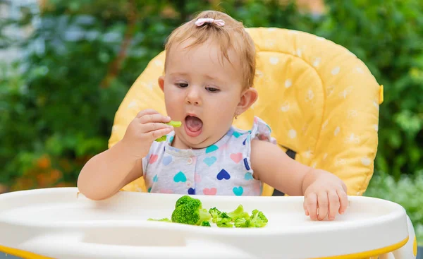 El bebé come trozos de verduras de brócoli. Enfoque selectivo. —  Fotos de Stock