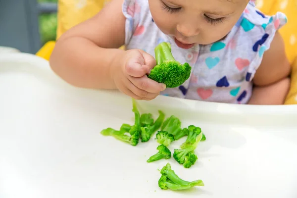 O bebé come pedaços de brócolis. Foco seletivo. — Fotografia de Stock