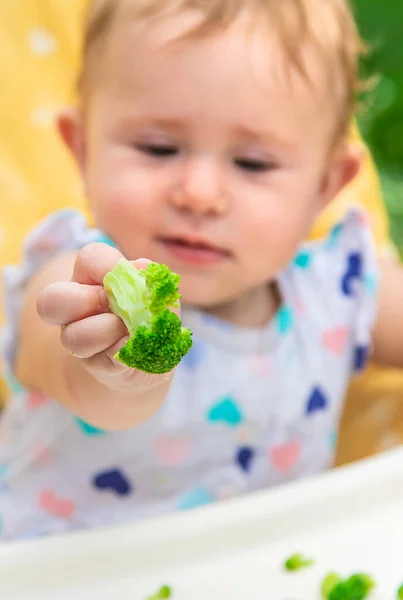 Baby eats pieces of broccoli vegetables. Selective focus. — Stock Photo, Image