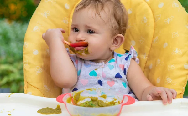 O bebé está a comer puré de legumes. Foco seletivo. — Fotografia de Stock