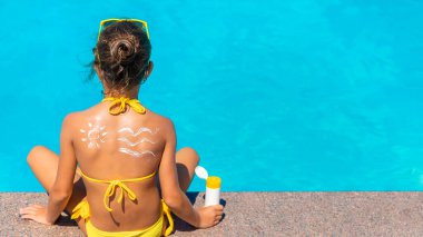 Çocuğun arkasında güneş kremi var. Seçici odak.