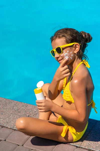 Protector solar cerca de la piscina en la cara del niño. Enfoque selectivo. — Foto de Stock