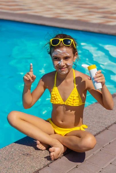 Çocuğun yüzünde havuzun yanında güneş kremi var. Seçici odak. — Stok fotoğraf