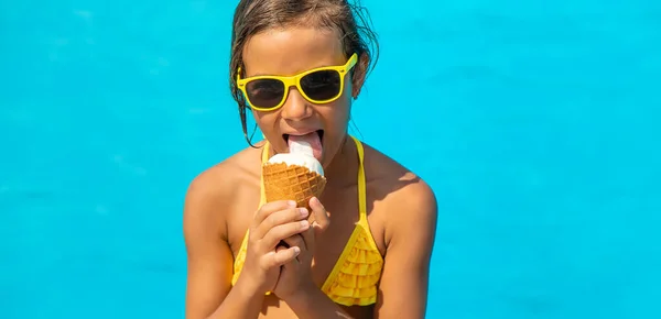 L'enfant mange de la glace près de la piscine. Concentration sélective. — Photo