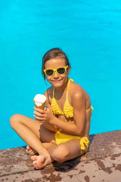 El niño está comiendo helado cerca de la piscina. Enfoque selectivo. — Foto de Stock