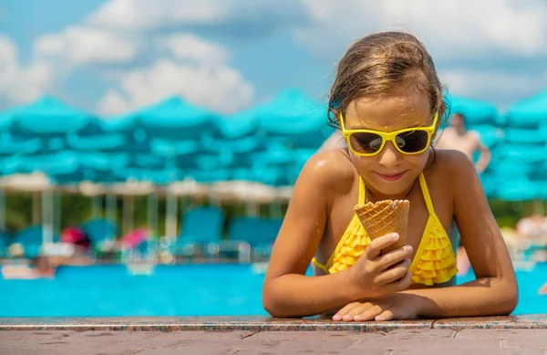 L'enfant mange de la glace près de la piscine. Concentration sélective. — Photo