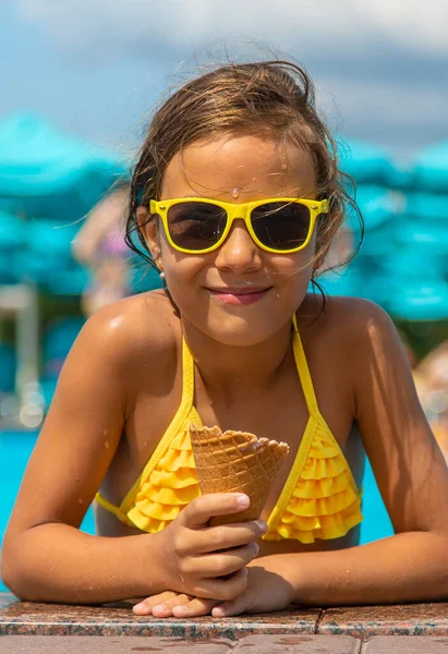 The child is eating ice cream near the pool. Selective focus. — Stock Photo, Image