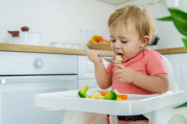 Bebek sandalyede sebze yiyor. Seçici odak.