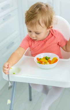 Bebek sandalyede sebze yiyor. Seçici odak.