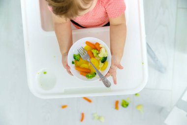 Bebek sandalyede sebze yiyor. Seçici odak.