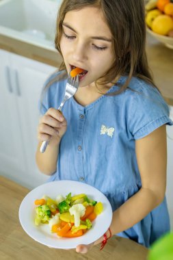 Çocuk sandalyede sebze yiyor. Seçici odak.