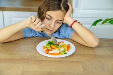 Çocuk sandalyede sebze yiyor. Seçici odak.