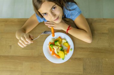 Çocuk sandalyede sebze yiyor. Seçici odak.