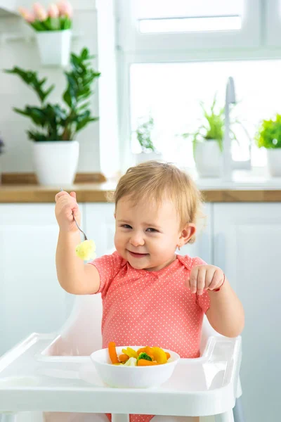 Το μωρό τρώει λαχανικά σε μια καρέκλα. Επιλεκτική εστίαση. — Φωτογραφία Αρχείου