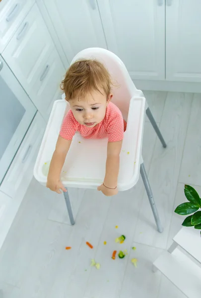 Dítě jí zeleninu na židli. Selektivní zaměření. — Stock fotografie