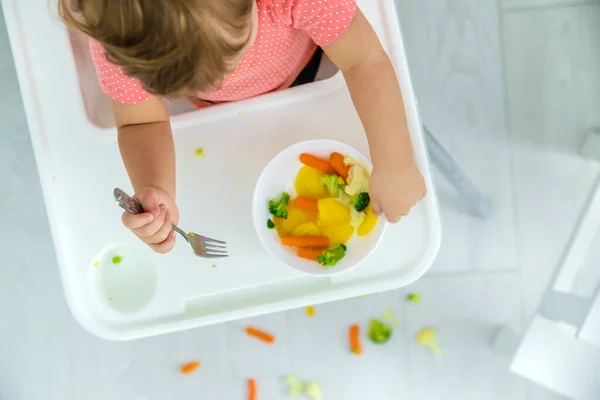 아기는 의자에서 야채를 먹는다. 선택적 초점. — 스톡 사진