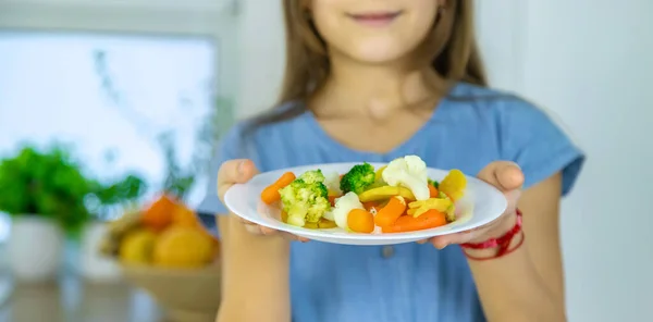 Il bambino mangia verdure su una sedia. Focus selettivo. — Foto Stock