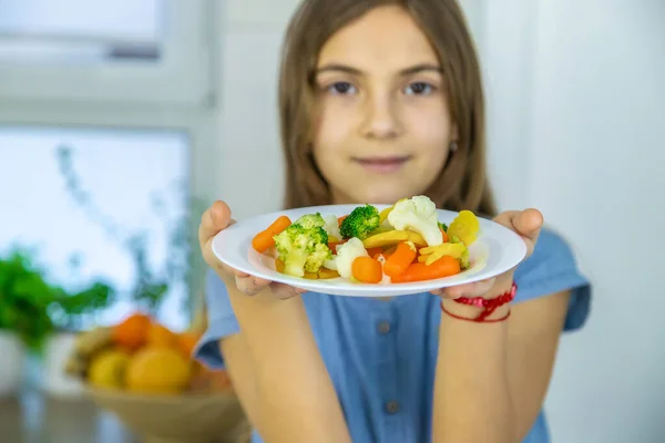 A criança come verduras em uma cadeira. Foco seletivo. — Fotografia de Stock