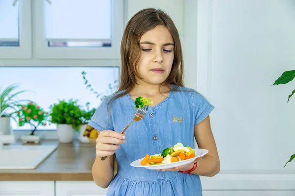 To dítě jí zeleninu na židli. Selektivní zaměření. — Stock fotografie